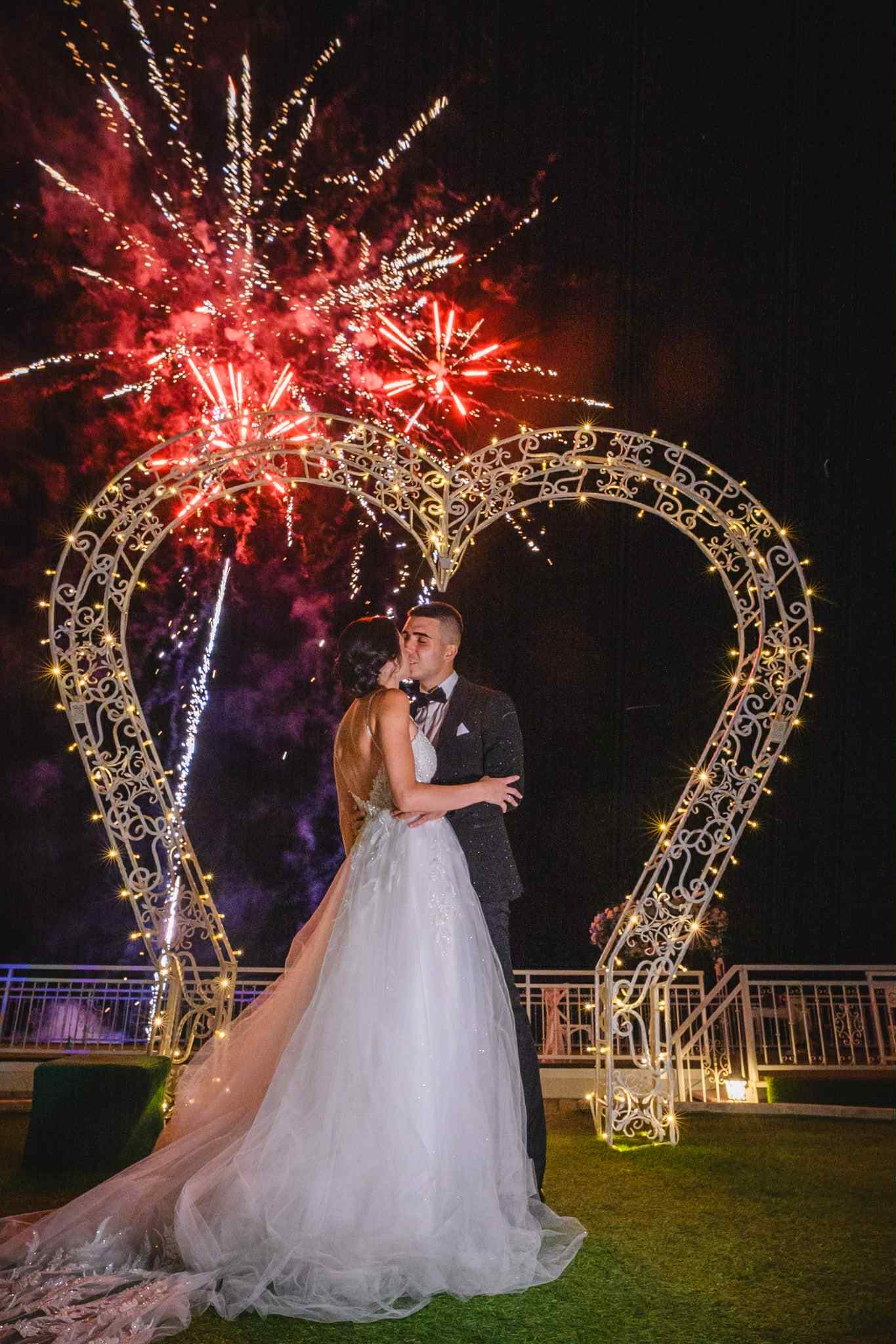 The newlyweds kissing beneath fireworks