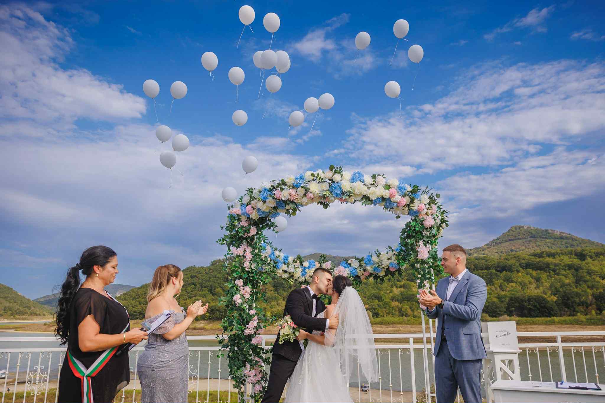 The outdoor ceremony beneath an arch by the water