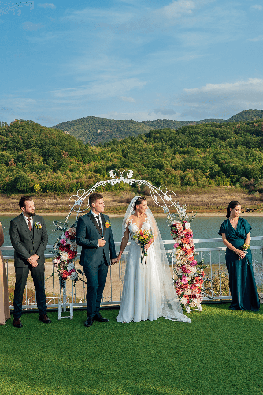 Newlyweds beneath an arch on the waterside terrace